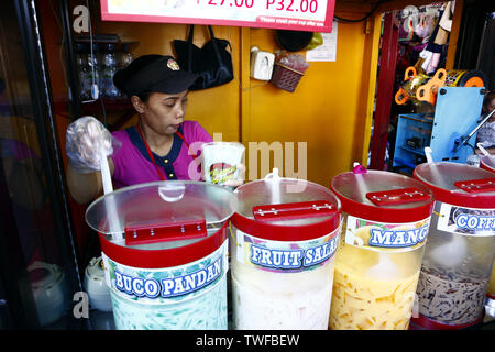 ANTIPOLO CITY, Philippinen - 18. JUNI 2019: eine Frau verkauft verschiedene Fruchtsäfte und andere Erfrischungen an einem heißen Sommertag. Stockfoto
