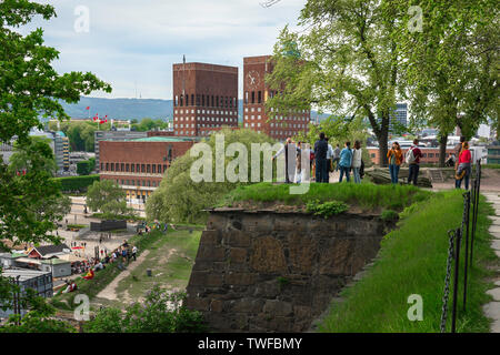 Oslo, Blick auf Menschen, die auf den Wällen der Akershus Festning (Festung) stehen und auf das Rathaus von Oslo im Hafengebiet, Norwegen, schauen Stockfoto