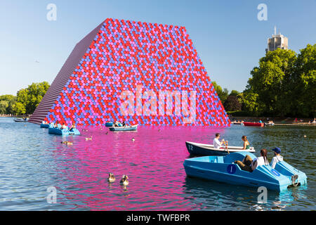 Sportboote auf See Serpentine Lake im Hyde Park mit dem Londoner Mastaba kunst Installation von Christo und Jeanne-Claude im Hintergrund. Stockfoto