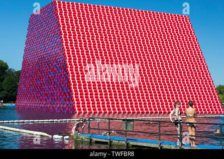 Outdoor Schwimmen im See Serpentine Lake im Hyde Park mit dem Londoner Mastaba kunst Installation von Christo und Jeanne-Claude im Hintergrund. Stockfoto