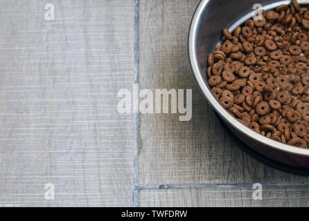 Trockenfutter für Katzen und Hunde in Aluminium Teller auf dem Boden Hintergrund. Tierische Nahrung metallic Edelstahl pet-Schüssel. Stockfoto