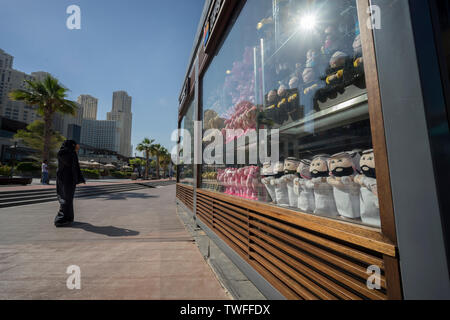 Eine Frau geht hinter einem Schaufenster mit arabischen Souvenirs in Dubai gefüllt. Stockfoto