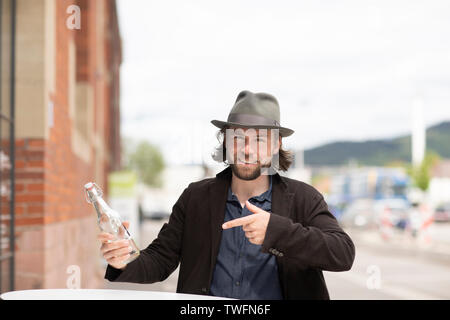 Porträt eines lächelnden Mann an eine Flasche Wasser zeigen Stockfoto