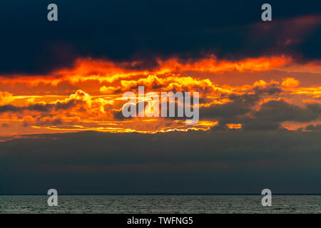 Burning Skies mit orange Wolken wie Feuer im Himmel kurz nach Sonnenuntergang am Meer. Stockfoto