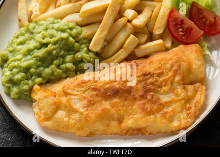 Ein seelachsfilet, Pollachius pollachius, dass in hausgemachter Teig beschichtet ist und frittiert und mit Erbsenpüree und Chips serviert. Der Pollack war Stockfoto