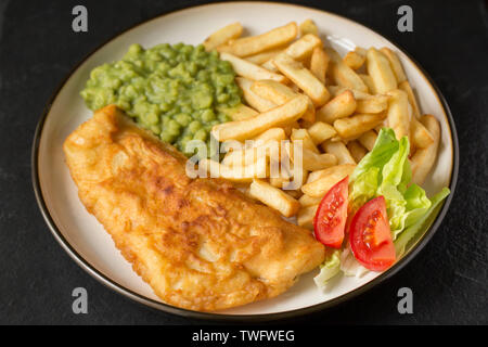 Ein seelachsfilet, Pollachius pollachius, dass in hausgemachter Teig beschichtet ist und frittiert und mit Erbsenpüree und Chips serviert. Der Pollack war Stockfoto