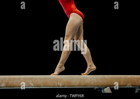 Weibliche Gymnast in Rot body Performance auf schwebebalken auf schwarzem Hintergrund Stockfoto