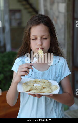 Mädchen isst Teigtaschen mit Quark Stockfoto