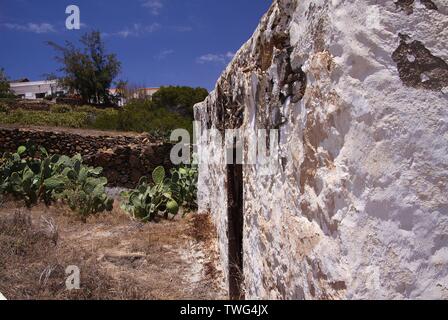 BETANCURIA, Fuerteventura - JUIN 14. 2019: Blick entlang der Wand des alten weißen Bauernhof mit Kakteen Garten gegen den blauen Himmel Stockfoto