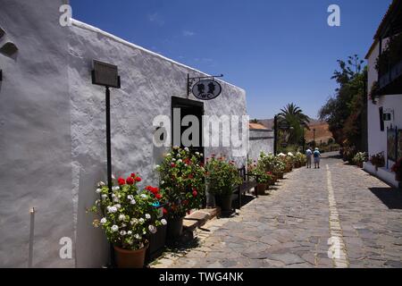 BETANCURIA, Fuerteventura - JUIN 14. 2019: Blick entlang der Straße mit öffentlichen Wc in traditionellen weißen Haus und Töpfe mit bunten Blumen Stockfoto