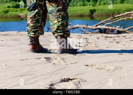 Männer Füße in die Schuhe auf dem Sand am Fluss Stockfoto