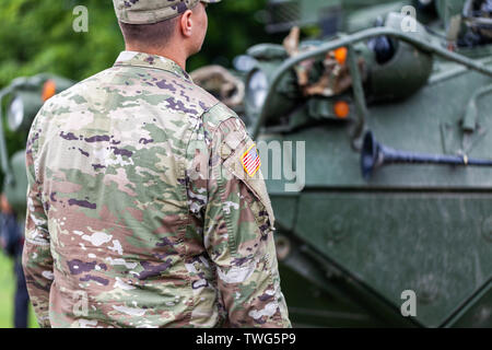 Ein Soldat von der United States Army steht vor einem gepanzerten Fahrzeug Stockfoto