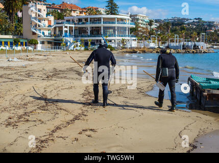 Männer in Tauchanzüge mit Metalldetektoren auf dem öffentlichen Strand. Selektive konzentrieren. Stockfoto