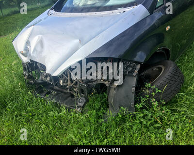 Das Wrack des Auto steht auf dem Gras mit gebrochenen Rad und ohne die vorderen Teile. Vielleicht nach der Frontalaufprall. Stockfoto