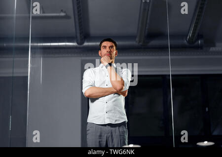 Geschäftsmann an der Glaswand in der Nacht Büro suchen Stockfoto