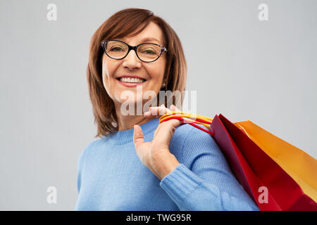 Ältere Frau mit Einkaufstüten über Grau Stockfoto