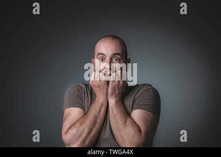 Portrait der kaukasischen Mann mit Angst Ausdruck seine Hände in seinem Gesicht, Studio gedreht. Stockfoto