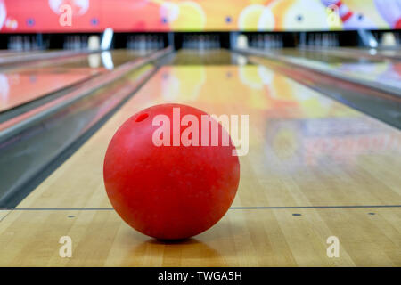 Red Bowling Ball auf Holz Gasse mit unscharfen Bowling Pin Hintergrund Stockfoto