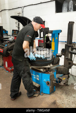 Mechaniker ändern Autoreifen mit Maschine. Bury Reifen Center in Bury St. Edmunds, Suffolk, Großbritannien Stockfoto