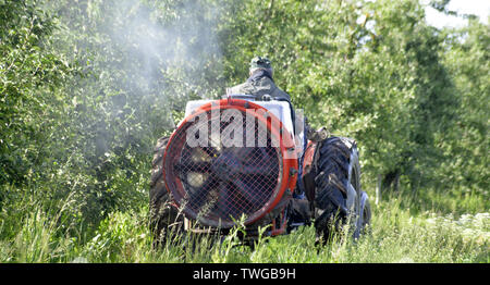 Traktor sprays Insektengift in Apple Orchard Felder Bild Stockfoto