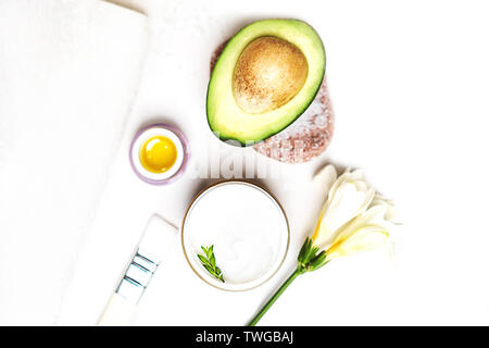 Avocado- und jar-Creme Öl lily Blumen und Meersalz Seife weisses Handtuch auf einem weißen Hintergrund. Stockfoto