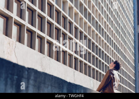 Der Mensch in der beiläufigen Tuch gegen industrielle Gebäude posing Stockfoto