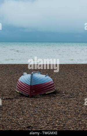 Umgedrehten blau und rot Ruderboot auf einem Kieselstrand Stockfoto