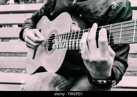Der Musiker spielt schön seine schöne Gitarre und close-up Griffbrett mit Zeichenfolgen, die durch seine Finger geklemmt Stockfoto