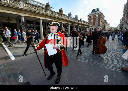 London, Großbritannien. 20. Juni 2019. Alan Myatt, stadtausrufer, und einer Blaskapelle nehmen Sie Teil an den historischen "Mieten Zeremonie" in Covent Garden. Eine Parade des Kuratoriums der Covent Garden Area Vertrauen begleitet von der Oberbürgermeister von Westminster, stellvertretender Bürgermeister von Camden und andere dignatories sowie Straßenkünstler März rund um die Piazza, wo das Kuratorium einen symbolischen "Pfeffer Miete zahlen", bestehend aus fünf Rosige rote Äpfel und fünf posies von Blumen und posies sind als Miete an den Vermieter gezahlt. Credit: Stephen Chung/Alamy leben Nachrichten Stockfoto