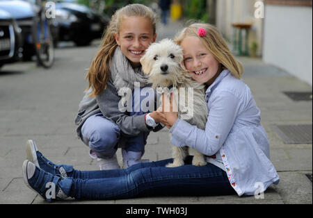 Zwei Schwestern mit ihren kreuzen Hund auf einem Bürgersteig in Düsseldorf, Deutschland. Stockfoto