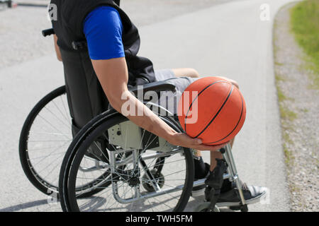 Behinderte junge basketballspieler auf einen Rollstuhl holding Ball und beeing Aktiv im Sport Stockfoto