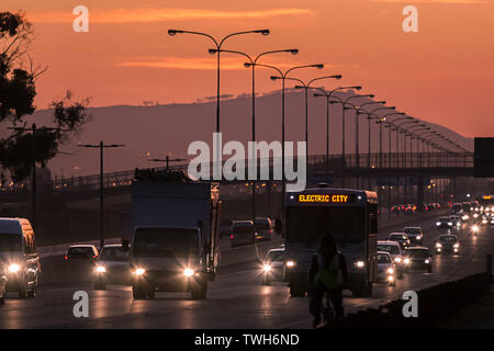 Ein Blick auf den Datenverkehr auf einer Bundesstraße in der Stadt Kapstadt, Südafrika in der Abenddämmerung. Stockfoto