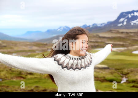 Gerne freie Frau auf Island auf Isländisch Pullover. Portrait von Mädchen glücklich lächelnde draußen in der Natur tragen Isländische Pullover. Hübsche asiatische Kaukasischen multirassischen weibliche Modell Stockfoto