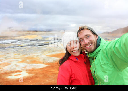 Island Touristen Paar unter selfie Foto mit Smartphone Kamera im Landmark Ziel: namafjall Hverarondor mudpot hverir auch als Schlammbad hot spring oder fumarole. Wunderschöne Natur Islands. Stockfoto