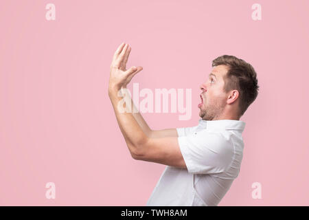 Schockiert, junger Mann im weißen Hemd mit weit geöffneten mouthlooking auf seine Hände. Stockfoto