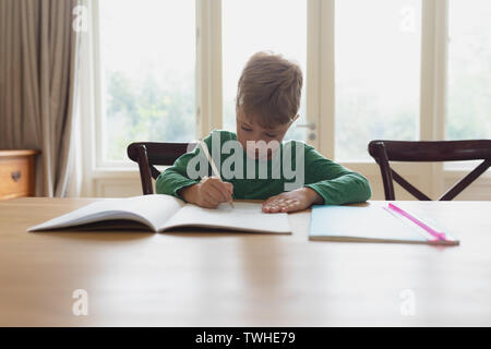 Cute boy Hausaufgaben am Esstisch in ein komfortables Zuhause tun Stockfoto
