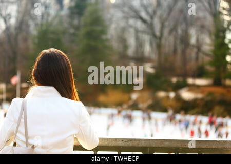 Central Park Eisbahn - die Frau, die in New York City im späten Herbst Winter mit Eisbahn im Hintergrund. Offenes Lächeln, multi-ethnischen Mädchen auf Manhattan, USA. Stockfoto