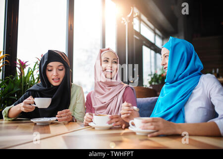 Junge muslimische Frauen trinken Kaffee im Cafe mit Freunden Stockfoto