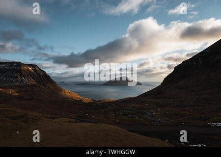 Am Abend Blick auf die Färöer Insel Koltur mit spektakulären Wolken, Sonne und blauer Himmel in einem dramatischen Tal mit Gebirge (Färöer Inseln) Stockfoto