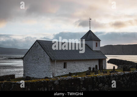 Kleine färöische Kirche in Kirkjubour während des Sonnenuntergangs auf einem Moody Frühling (Färöer, Dänemark, Europa) Stockfoto