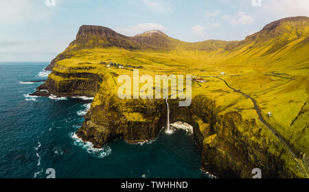 Luftbild des berühmten Gasadalur Wasserfall von oben an einem sonnigen Frühlingstag mit schneebedeckten Gipfeln und dark blue sea (Färöer Inseln) Stockfoto