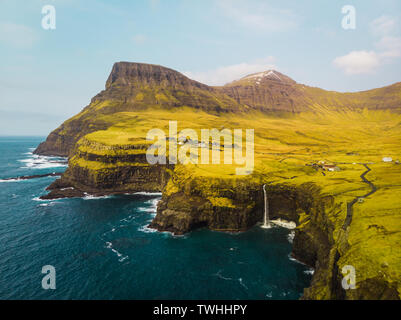 Luftbild des berühmten Gasadalur Wasserfall von oben an einem sonnigen Frühlingstag mit schneebedeckten Gipfeln und dark blue sea (Färöer Inseln) Stockfoto