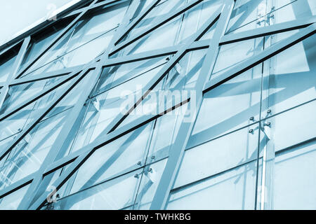 Abstrakte kommerzielle Architektur Hintergrund, Büro Gebäude Fassade mit geometrischen Stahlrahmen Muster und Glasscheiben. Blau getönten Foto Stockfoto