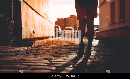 Silhouette eines Mädchens, die in den Strahlen der Sonne, Spaziergänge auf einem steinboden in einer europäischen Stadt, das Konzept der eine glückliche Reise, ein Urlaub in Europa Stockfoto