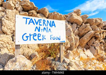 AMMOPI VILLAGE, Insel Karpathos - Sep 26, 2018: Weiße Zeichen der griechische Taverne vor Felsen auf Küstenweg in Ammopi Dorf. Griechische Inseln sind Fa Stockfoto