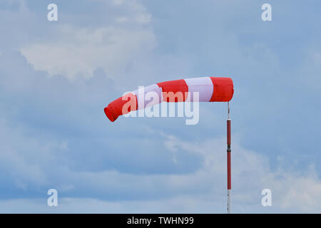 Windsack bei einem starken Wind. Windsack zeigt die Windrichtung und -stärke. Der Stoff in der Form eines Kegels. Es ist an den Flughäfen von kleinen Flugzeugen installiert Stockfoto