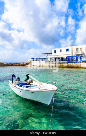 Weiß Fischerboot auf See im Ort Lefkos Port mit typischen Häuser am Ufer, Karpathos, Griechenland Stockfoto