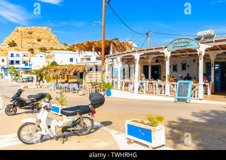 FINIKI HAFEN, Insel Karpathos - Sep 30, 2018: Motorroller Parkplatz vor der typisch griechischen Taverne auf der Straße von Finiki port, Karpathos, Griechenland. Stockfoto