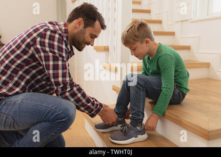 Vater seine Söhne Schnürsenkel binden in ein gemütliches Heim Stockfoto