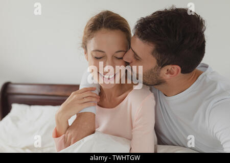 Mann küssen Frau auf dem Bett im Schlafzimmer Stockfoto
